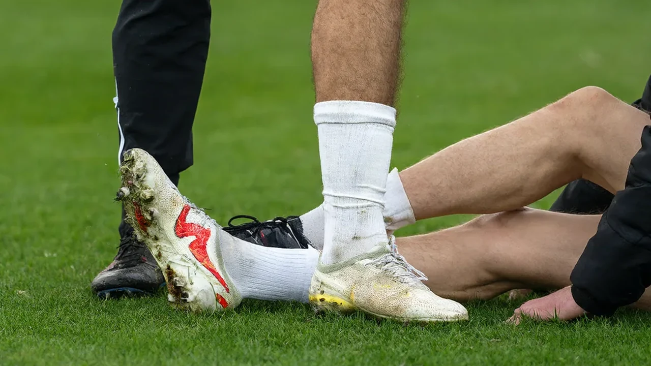 Footballer's lower leg and ankle being assessed by a physio on the touchline