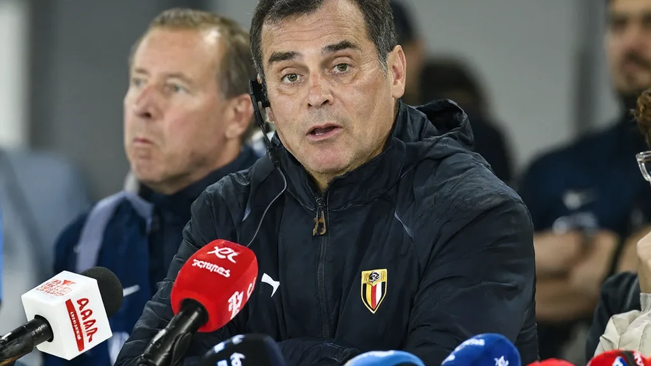 Coach speaking into microphones at a press conference