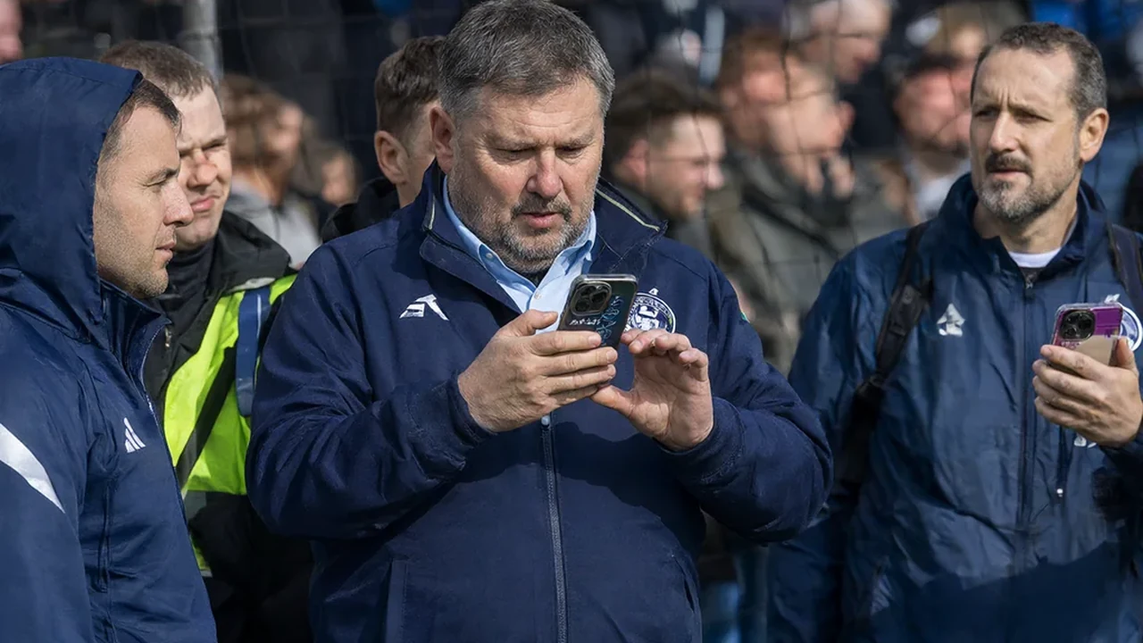 Fantasy football manager checking a phone with team news before kickoff