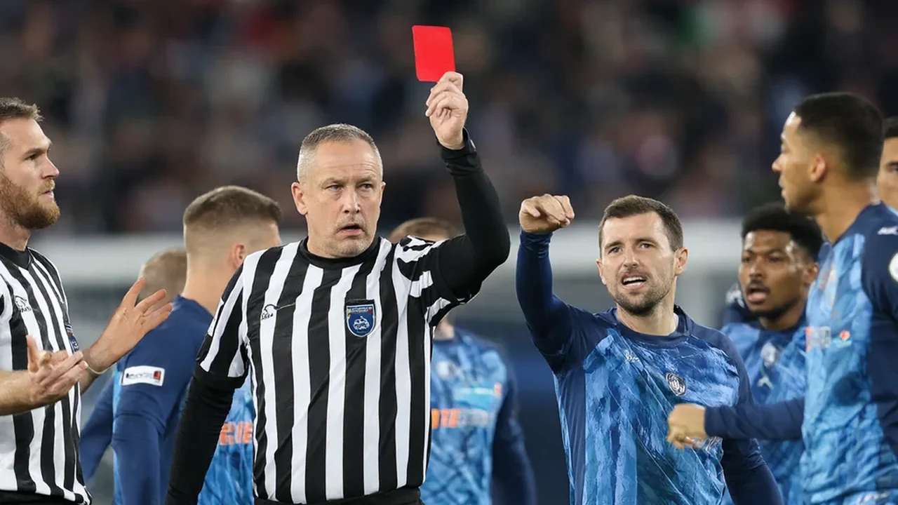 Referee holding up a red card as players react